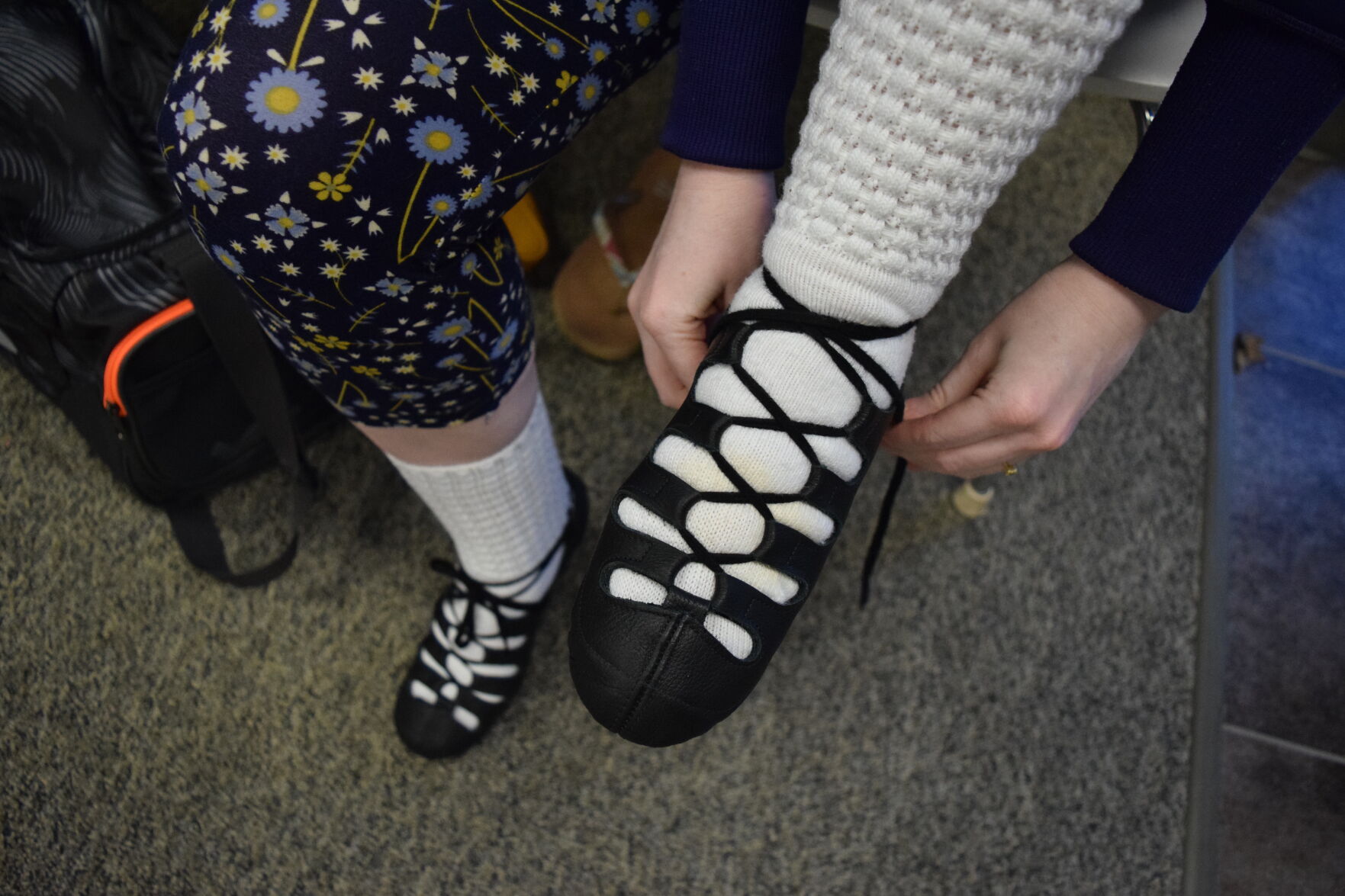 An Irish dancer ties her shoes at the Clark Academy of Irish Dance